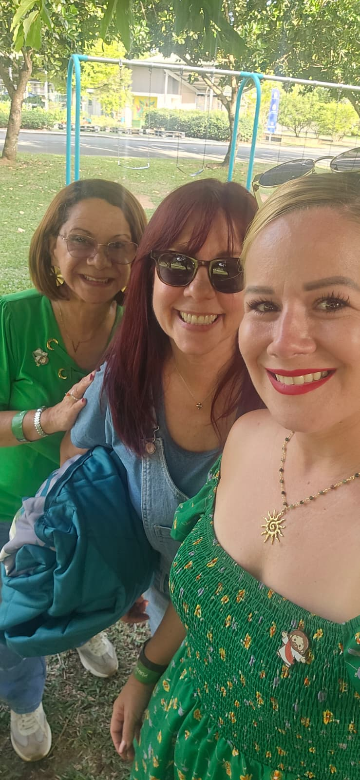 Tres integrantes de la comunidad sonríen juntas al aire libre
