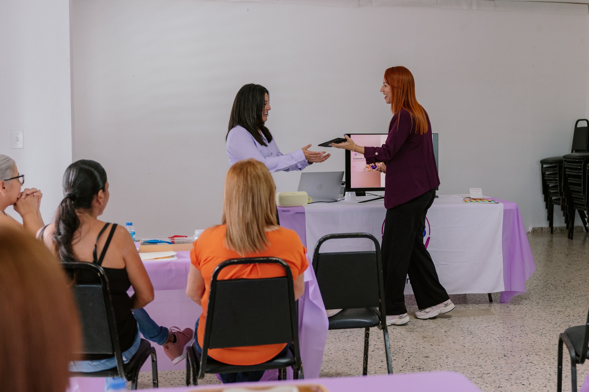 Mariluz le entrega a Lymari el celular para leer su semblanza durante un taller